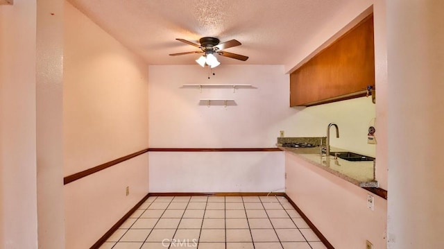 interior space featuring light tile patterned flooring, sink, ceiling fan, and a textured ceiling