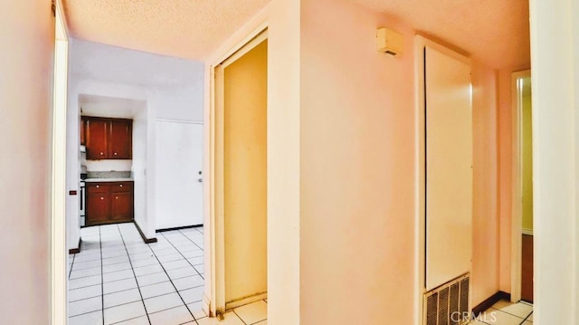 corridor with light tile patterned floors and a textured ceiling