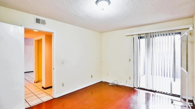 unfurnished room with a textured ceiling and light hardwood / wood-style flooring