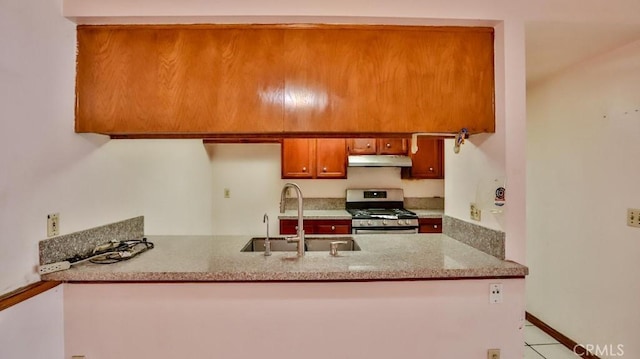 kitchen featuring sink, gas range, and light stone countertops