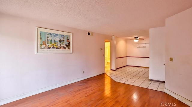 empty room featuring ceiling fan, a textured ceiling, and light hardwood / wood-style flooring