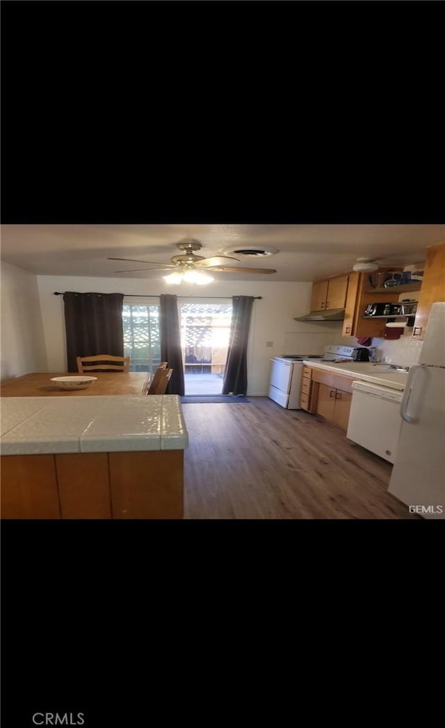 kitchen with tile counters, dark hardwood / wood-style flooring, kitchen peninsula, electric stove, and ceiling fan