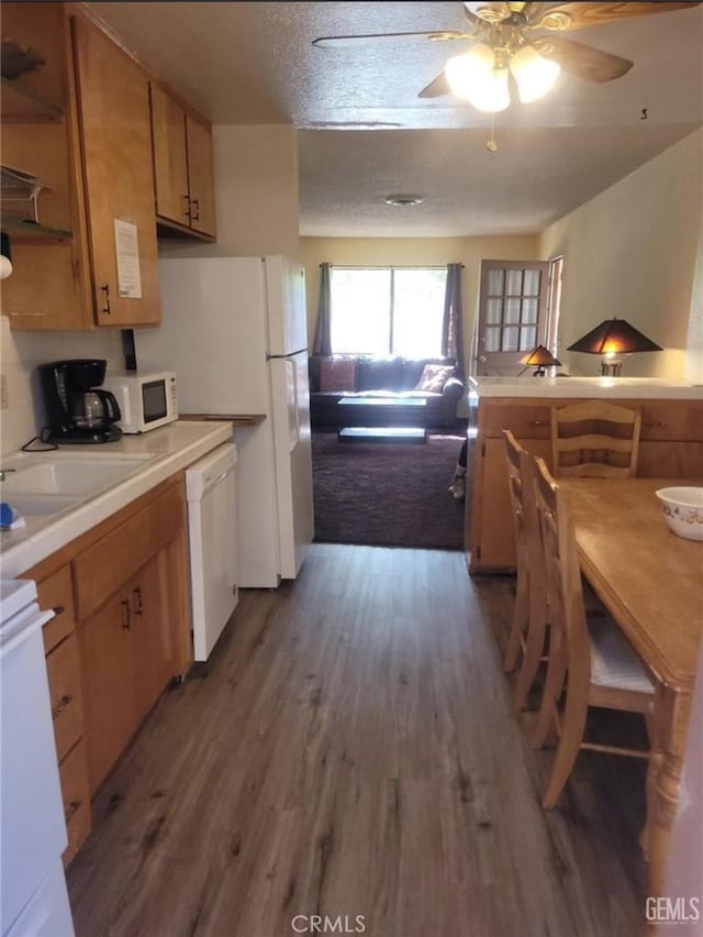 kitchen with sink, white appliances, wood-type flooring, a textured ceiling, and ceiling fan