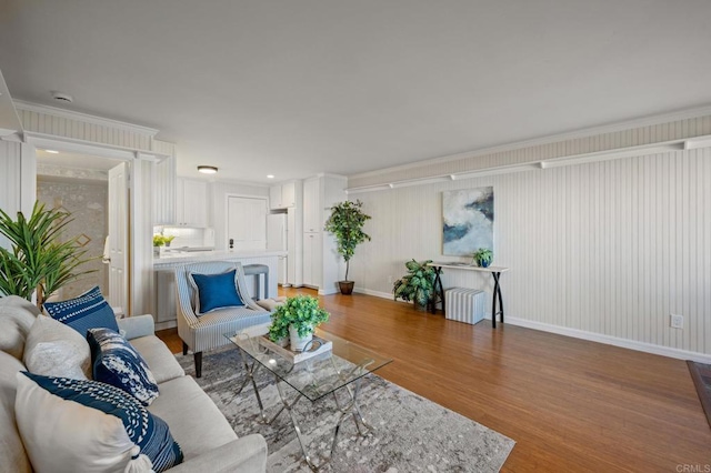 living area featuring radiator, baseboards, crown molding, and light wood finished floors