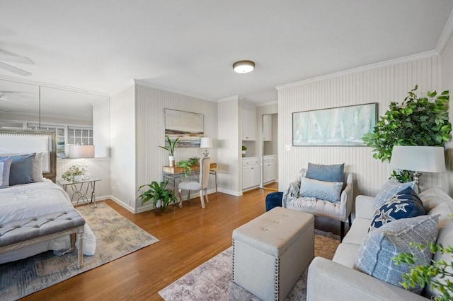 living area with ceiling fan, wood finished floors, baseboards, and ornamental molding