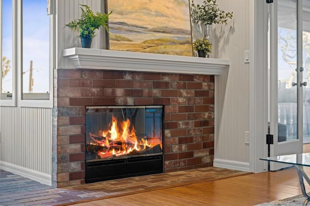 details featuring wood finished floors, a brick fireplace, and baseboards