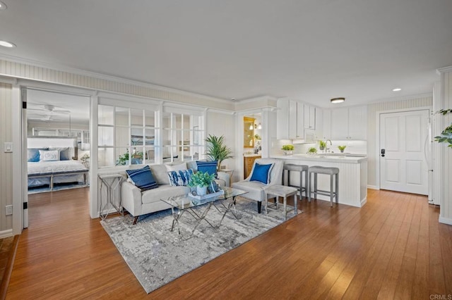 living room featuring wood-type flooring, ornamental molding, and recessed lighting