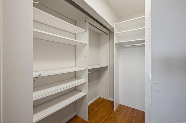 walk in closet with wood finished floors