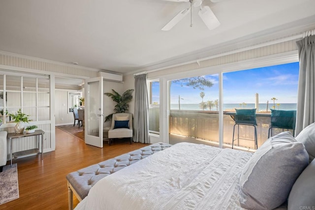 bedroom with a water view, crown molding, a wall mounted AC, access to outside, and multiple windows