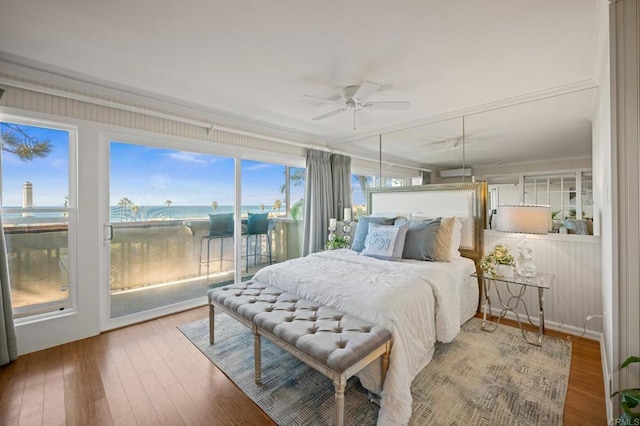 bedroom with wood finished floors, a water view, and access to exterior