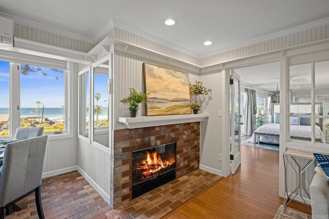 interior space featuring a water view, baseboards, recessed lighting, a brick fireplace, and ornamental molding