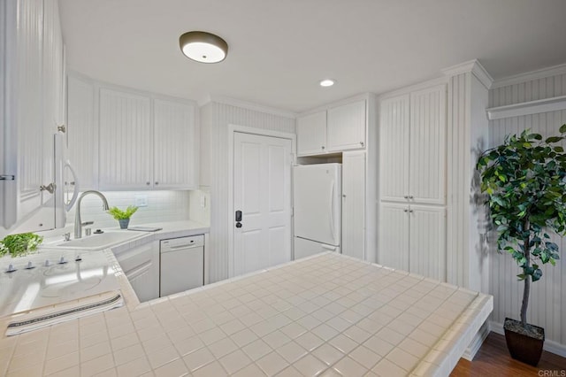 kitchen with a sink, backsplash, white cabinetry, white appliances, and crown molding
