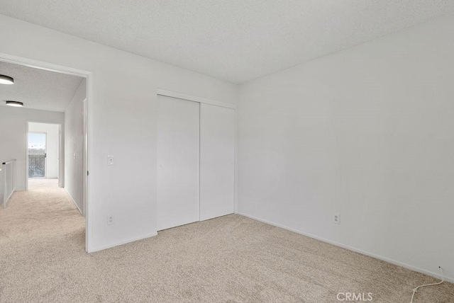 spare room with light colored carpet and a textured ceiling