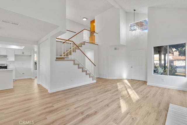 foyer entrance with light hardwood / wood-style flooring and high vaulted ceiling