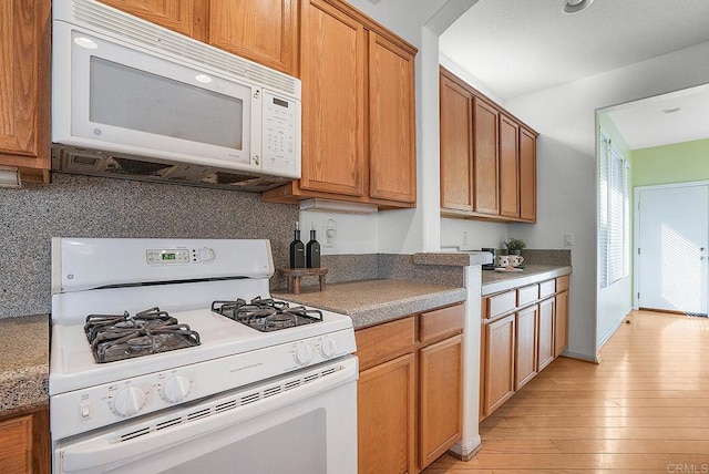 kitchen featuring backsplash, white appliances, and light hardwood / wood-style floors