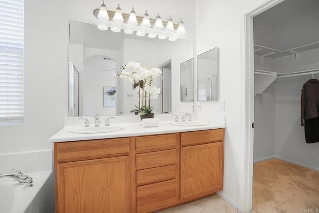 bathroom featuring a relaxing tiled tub and vanity