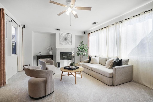 carpeted living room featuring a tiled fireplace and ceiling fan