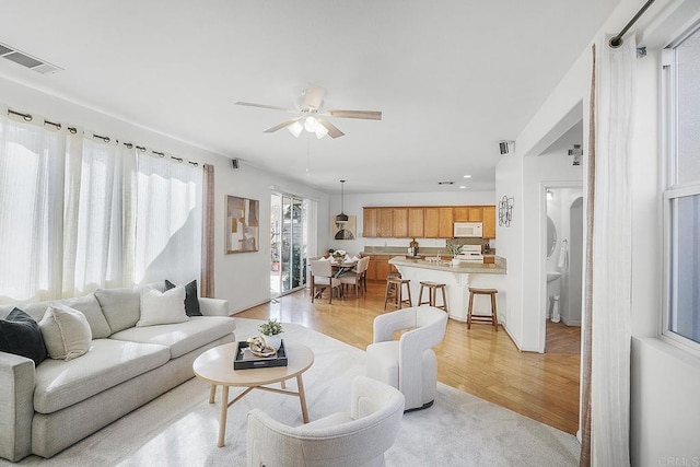 living room with ceiling fan and light wood-type flooring