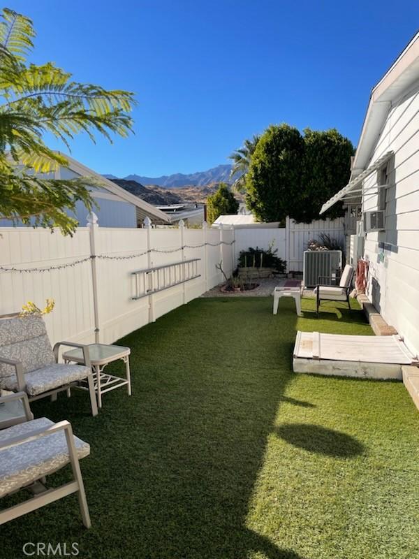 view of yard with a fenced backyard, a mountain view, and central AC