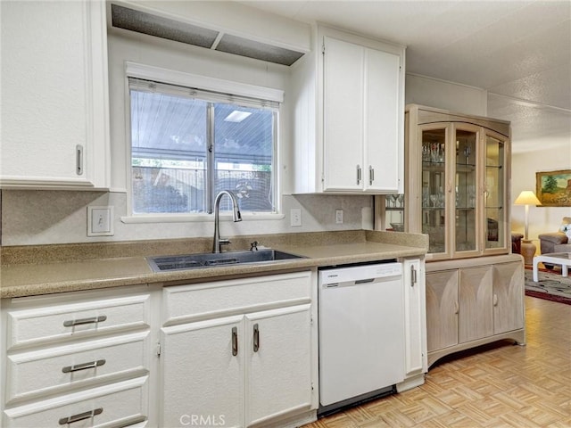 kitchen with light countertops, white cabinetry, white dishwasher, and a sink