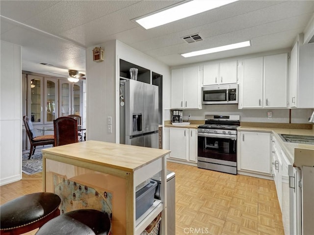 kitchen with stainless steel appliances, visible vents, a sink, and white cabinetry