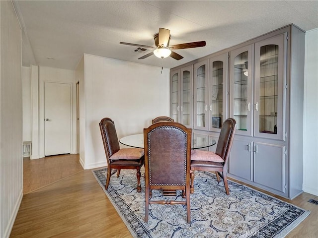 dining space featuring a textured ceiling, ceiling fan, and light wood-type flooring