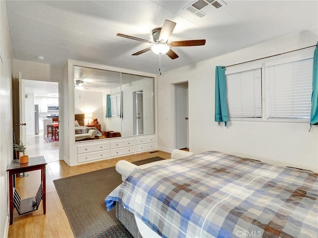 bedroom with ceiling fan, a closet, and light hardwood / wood-style flooring