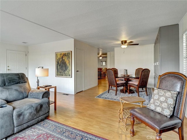 living room featuring visible vents, ceiling fan, a textured ceiling, and light wood finished floors