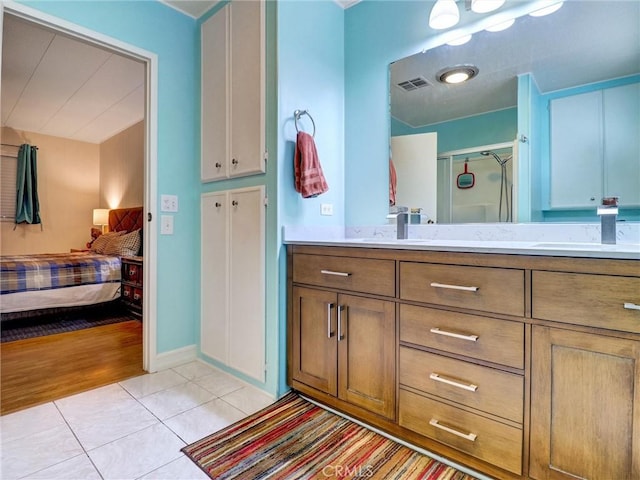 bathroom with double vanity, visible vents, a sink, a shower stall, and tile patterned flooring