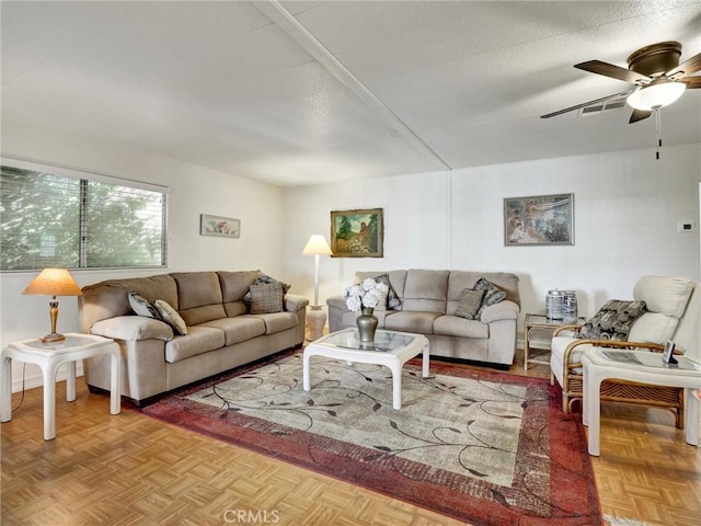 living room featuring ceiling fan, a textured ceiling, and light parquet floors