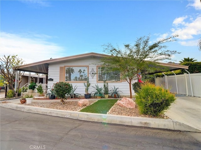 view of front of property featuring an attached carport, concrete driveway, and fence