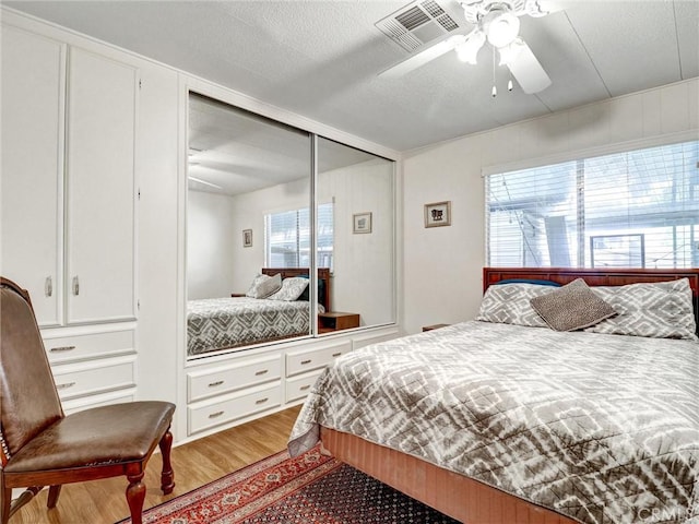 bedroom featuring visible vents, ceiling fan, a textured ceiling, and wood finished floors