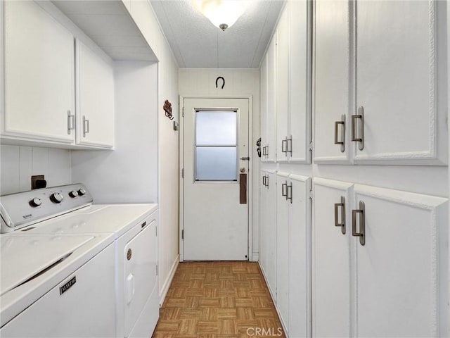 laundry room with a textured ceiling, washing machine and clothes dryer, and cabinet space