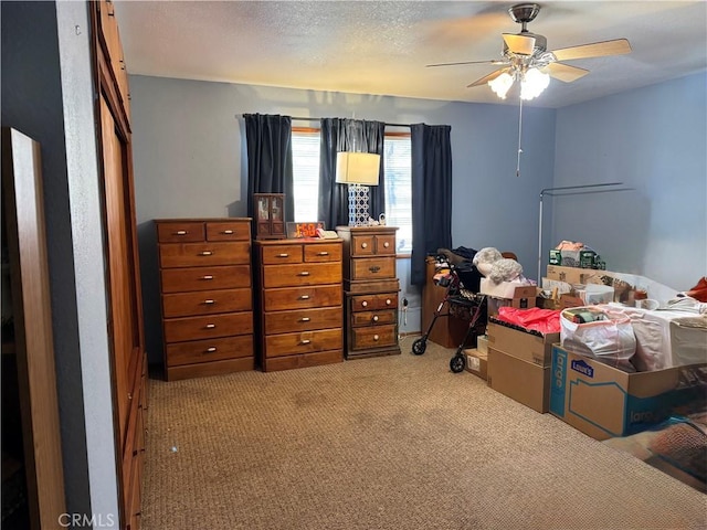 bedroom featuring light colored carpet, ceiling fan, and a textured ceiling