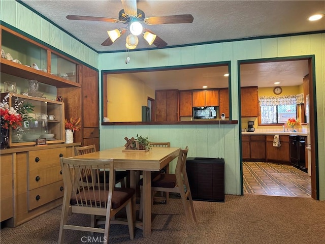 dining room featuring carpet, crown molding, a ceiling fan, wood walls, and a textured ceiling