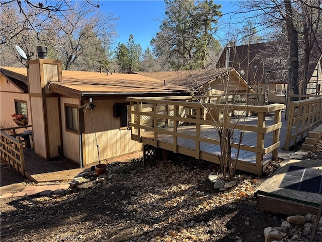 rear view of house with a shingled roof, a chimney, and a deck