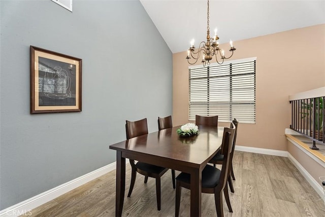 dining space with vaulted ceiling, a chandelier, and light hardwood / wood-style floors