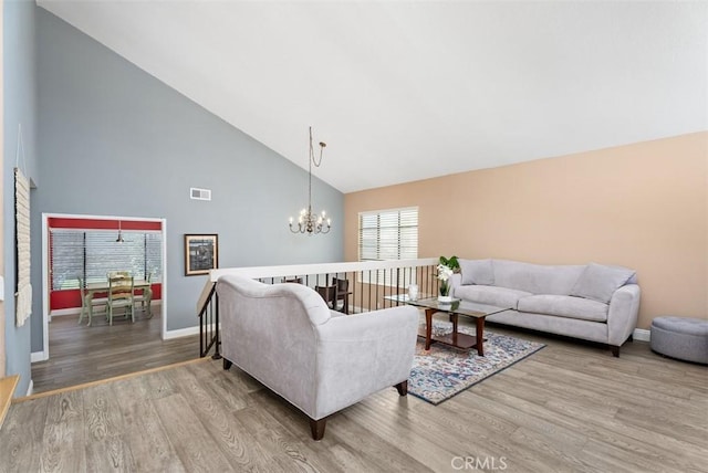 living room featuring a notable chandelier, wood-type flooring, and high vaulted ceiling