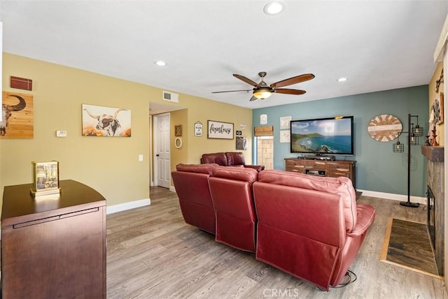 living room with ceiling fan, a fireplace, and light hardwood / wood-style flooring