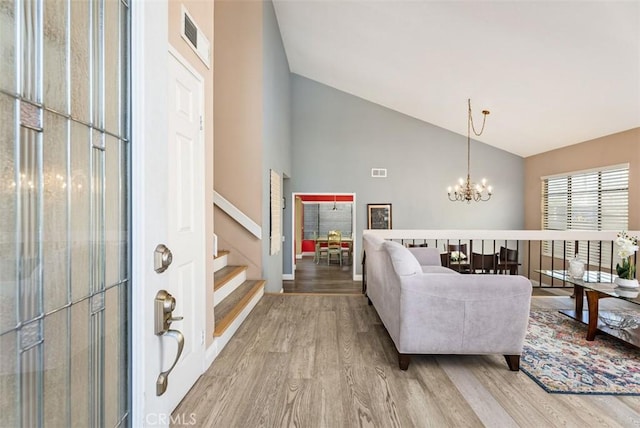 living room with hardwood / wood-style floors, high vaulted ceiling, and a chandelier