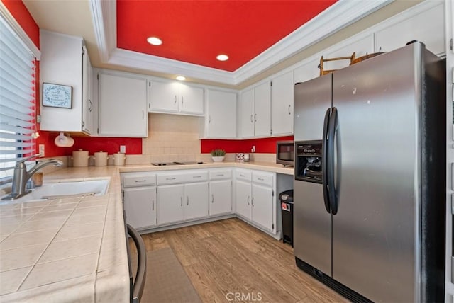 kitchen with sink, crown molding, a tray ceiling, stainless steel appliances, and white cabinets