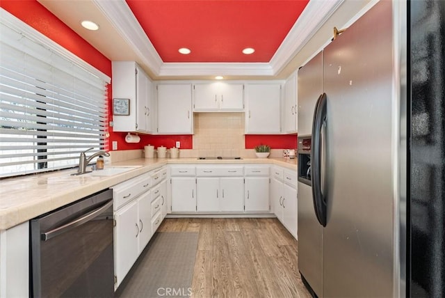 kitchen with white cabinetry, sink, ornamental molding, a tray ceiling, and stainless steel appliances