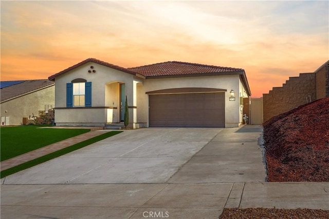 mediterranean / spanish-style home featuring a garage and a lawn