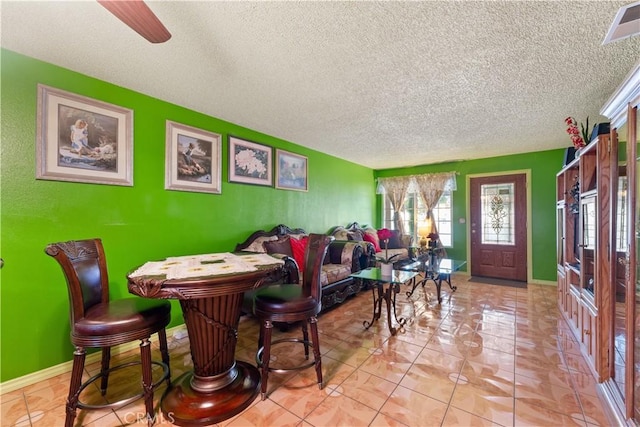 tiled dining space with ceiling fan and a textured ceiling