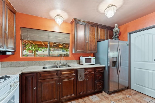 kitchen with light stone counters, sink, white appliances, and light tile patterned flooring