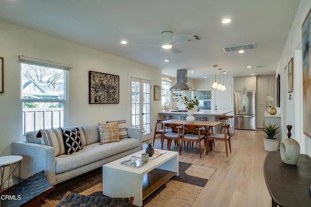 living room featuring french doors, ceiling fan, and light hardwood / wood-style flooring