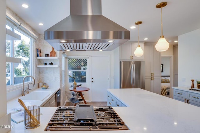 kitchen with sink, island range hood, appliances with stainless steel finishes, pendant lighting, and white cabinets