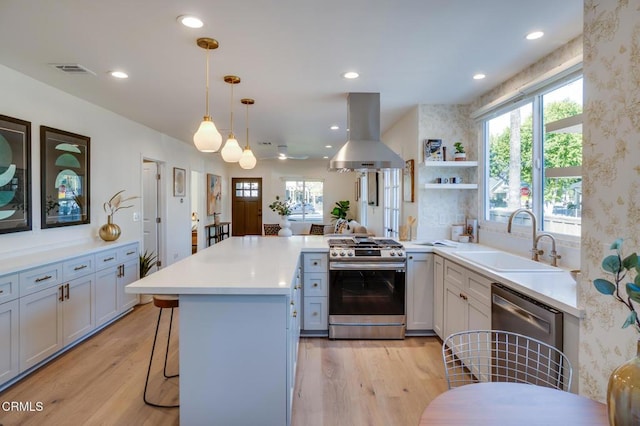 kitchen featuring island range hood, decorative light fixtures, sink, a kitchen breakfast bar, and stainless steel appliances