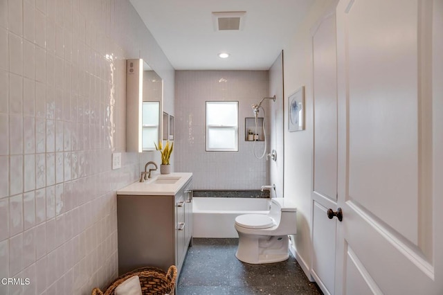 full bathroom with tile walls, vanity, tiled shower / bath combo, and toilet