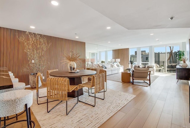 dining room with a wall of windows, light wood-type flooring, and recessed lighting